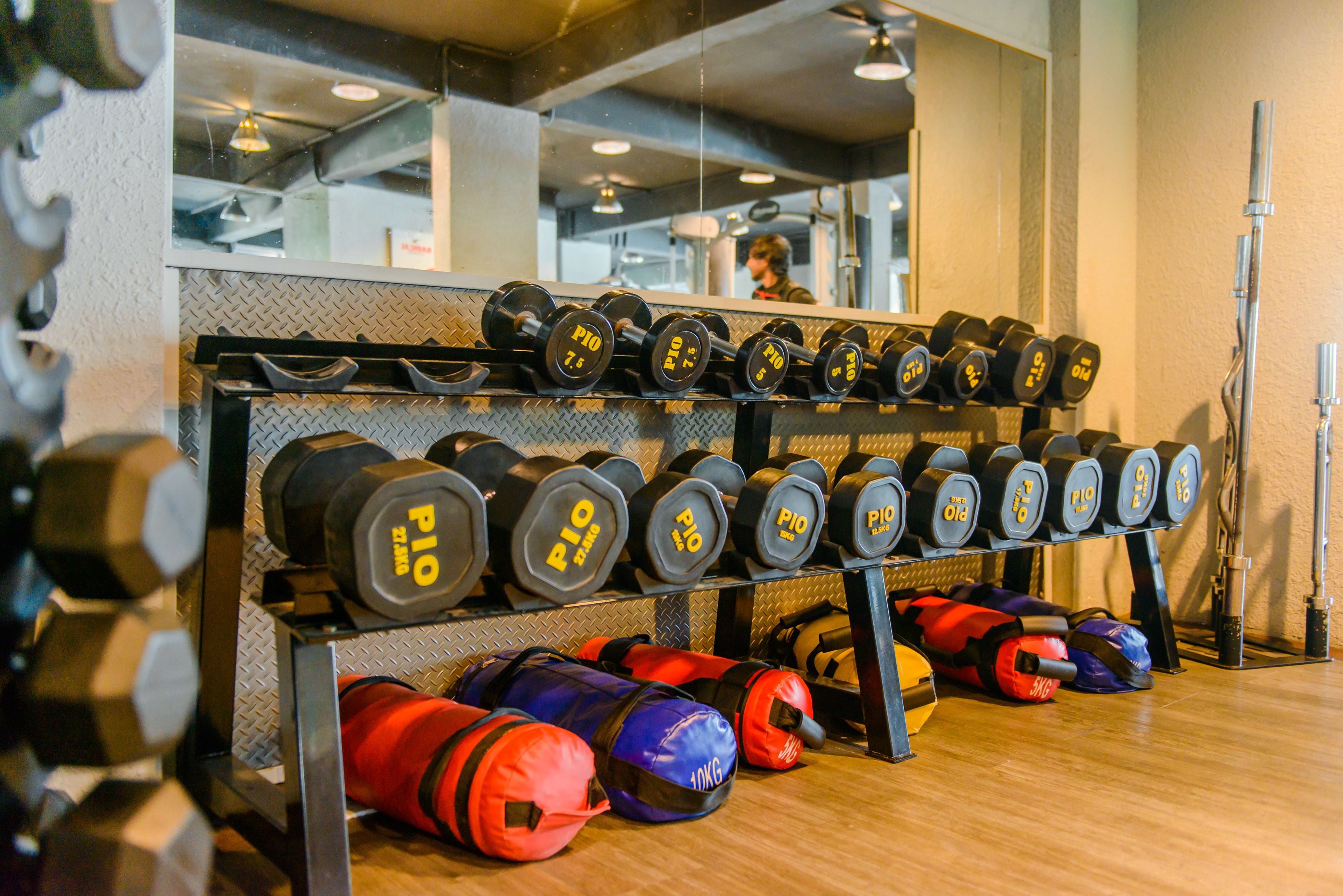 A gym with a rack of dumbbells and various bags of weights.