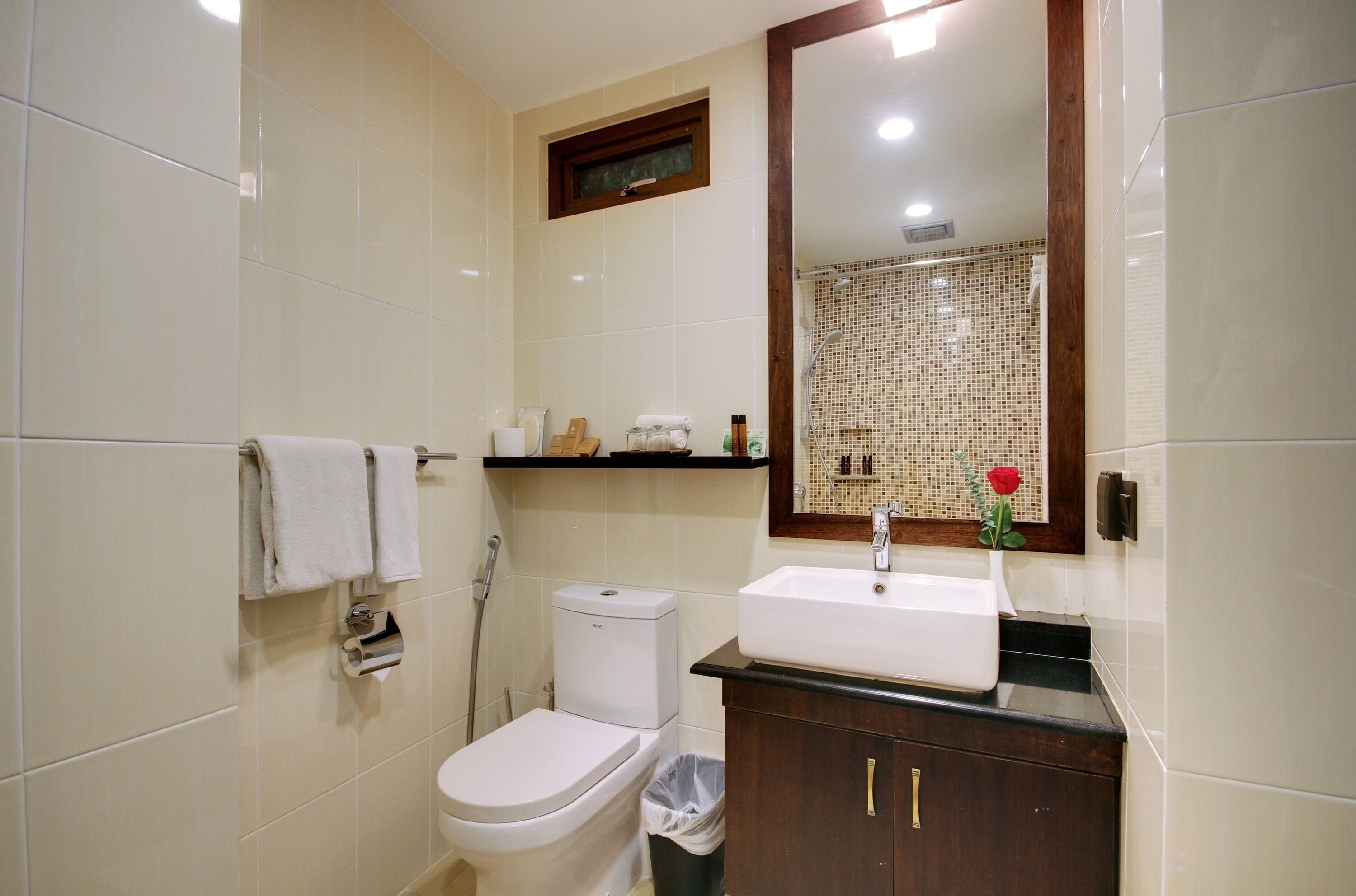 A bathroom with a toilet, sink, and mirror.