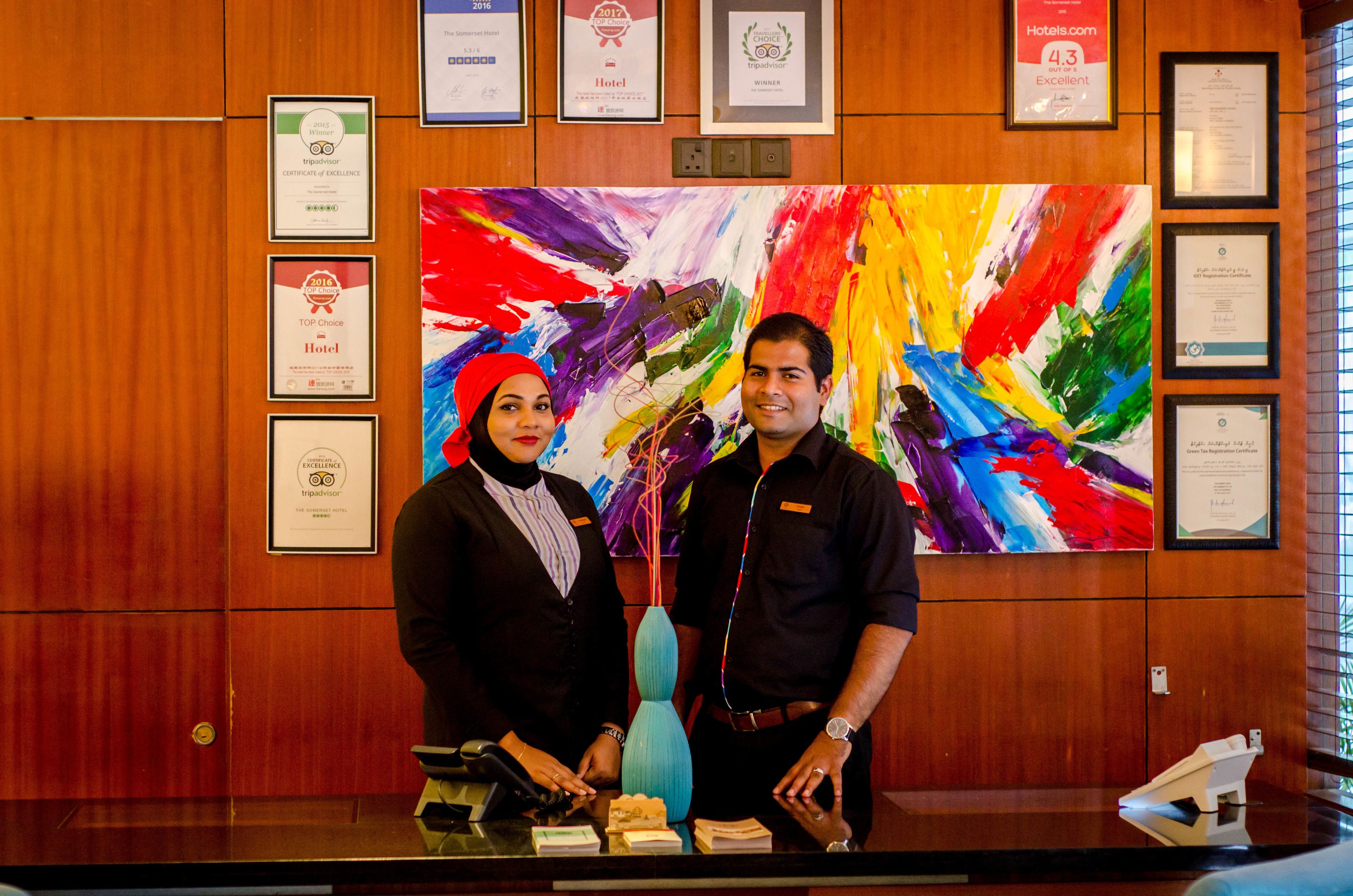 A reception desk with framed awards and a colorful abstract painting in the background.