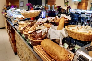 A buffet with various breads and pastries displayed in baskets. - The Somerset Hotel (Malé)