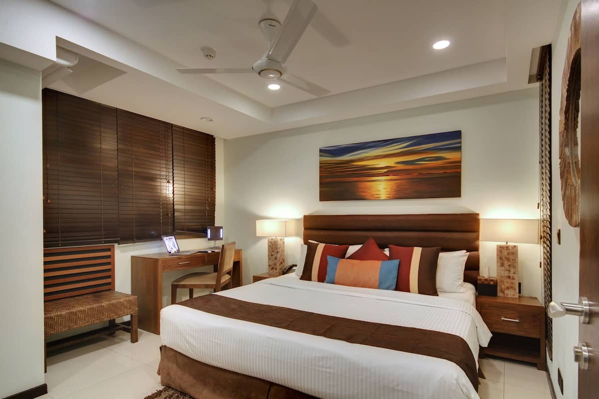 A modern bedroom with a large bed, a desk, and a chair.