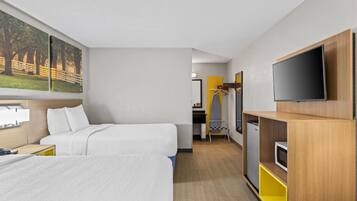 Una habitación de hotel con dos camas, televisión, escritorio y armario.