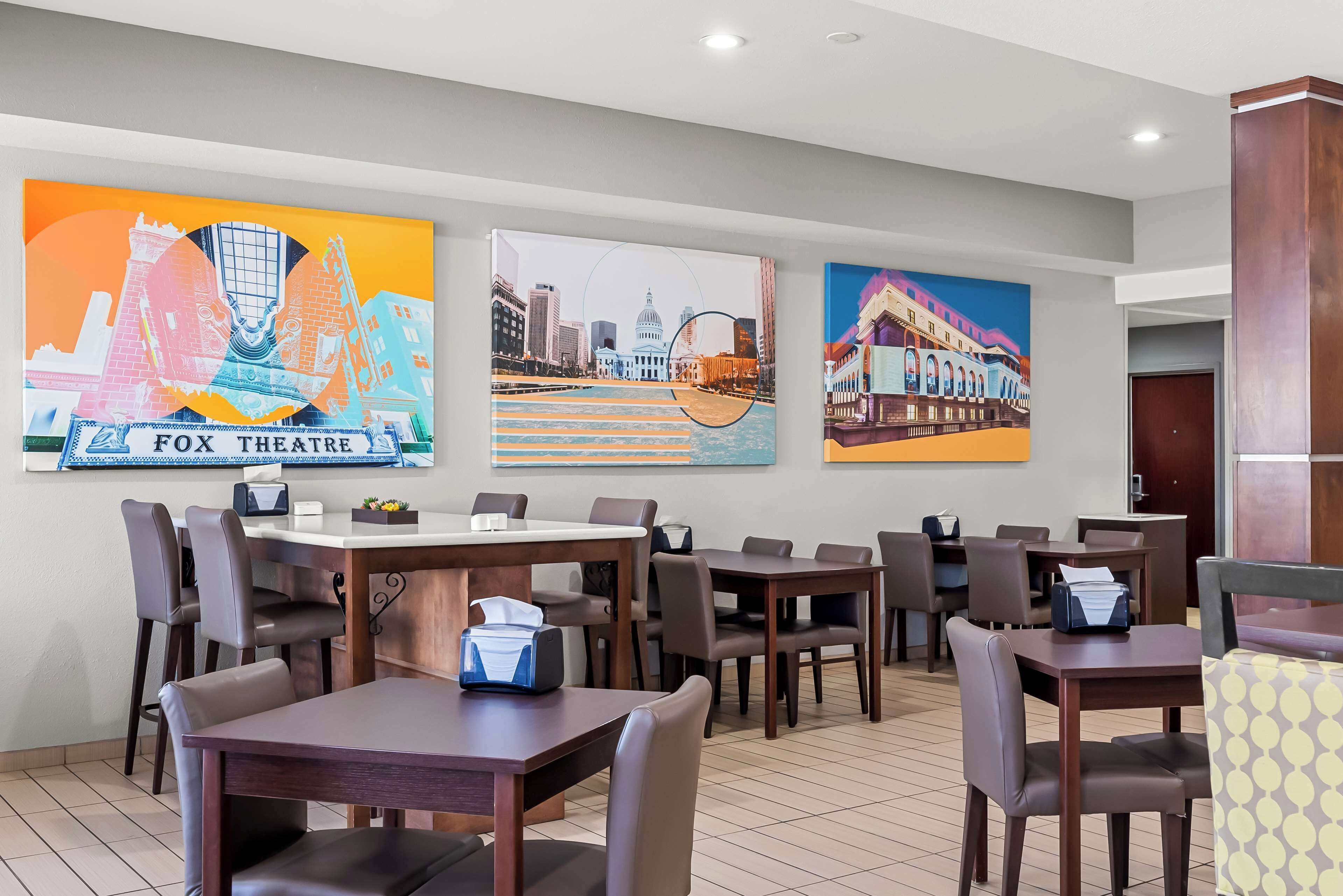 A hotel dining area with tables and chairs, a tissue box on one table, and three paintings on the wall.