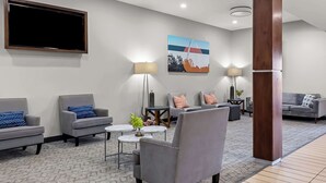 A modern living room with grey sofas, a coffee table, and a TV mounted on the wall. - Best Western St. Louis Airport North Hotel & Suites (Hazelwood)