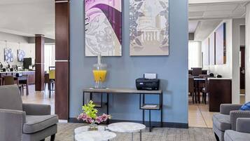 A hotel lobby with seating, a reception desk, and artwork on the walls.