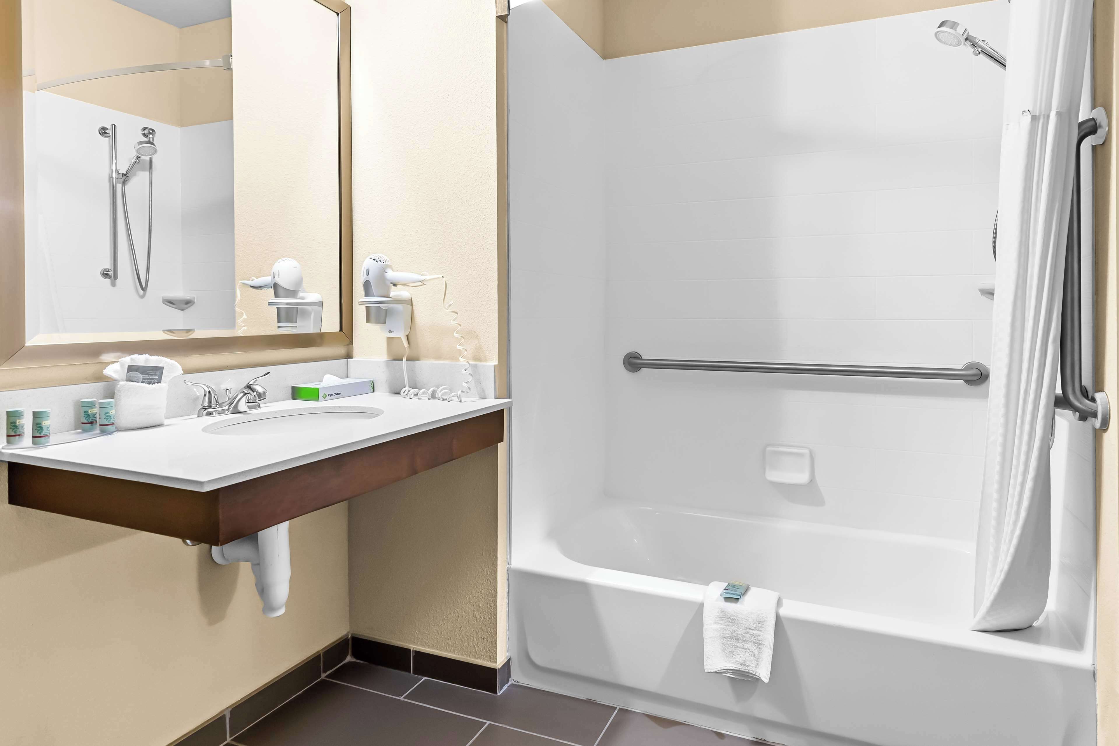 A bathroom with a sink, mirror, and shower.