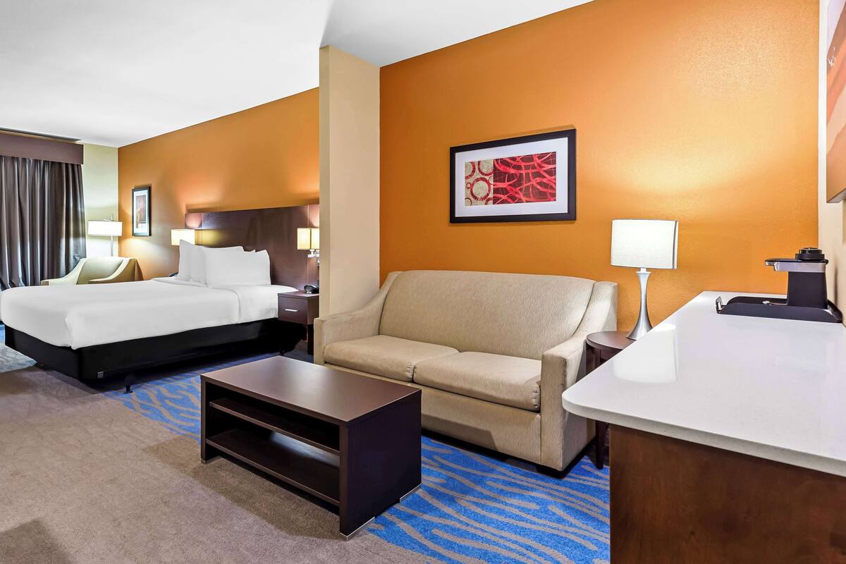 A hotel room with a bed, a sofa, a desk, and a coffee table.
