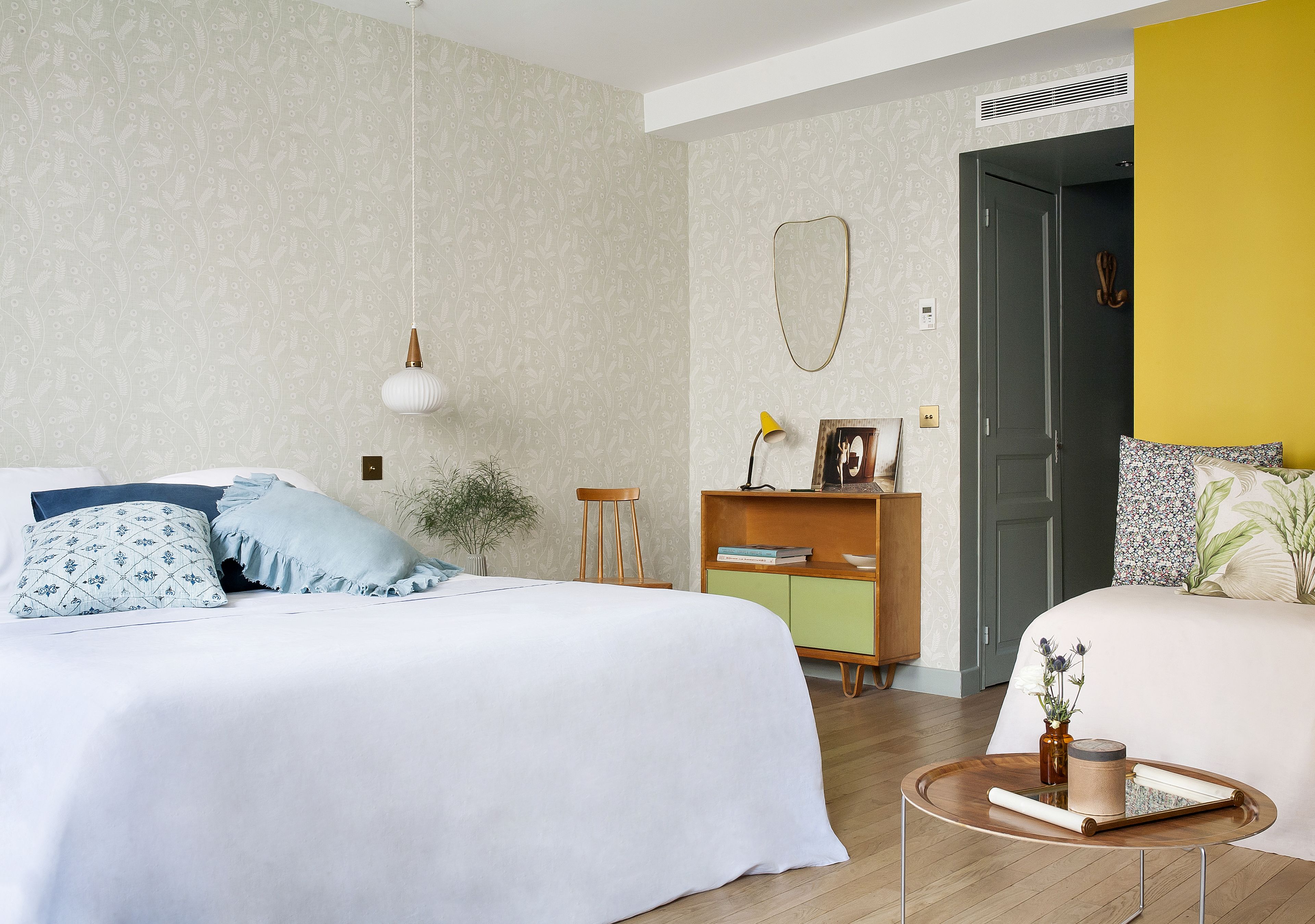 Ein Schlafzimmer mit zwei Betten, einem Nachttisch, einer Lampe, einem Spiegel und einer Kommode.