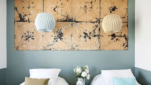 A hotel room with two beds, a vase with flowers, and a textured wall art piece. - Hôtel Henriette (Paris)
