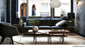 A modern living room with a blue sofa, two pendant lights, a coffee table, and a bookshelf. - Hôtel Henriette (Paris)