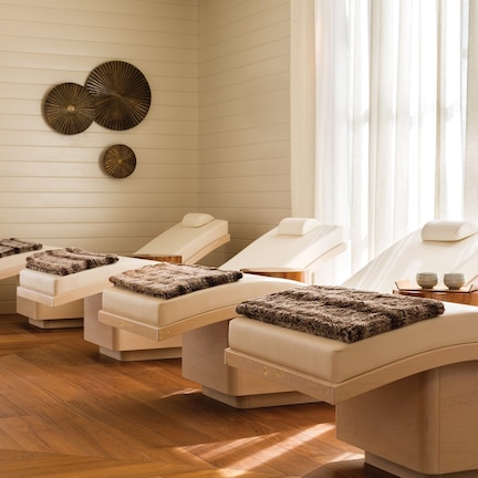 A spa room with three reclining chairs, each with a footrest and a small table.