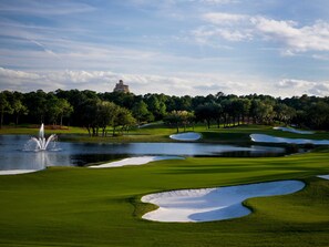 A golf course with sand bunkers, a pond, and trees.