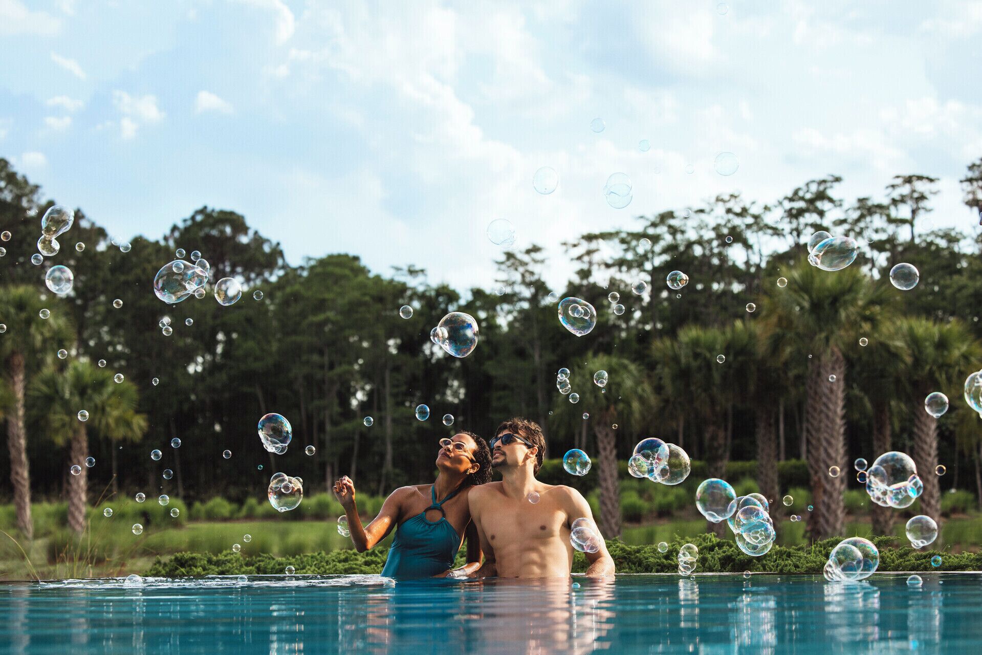 A swimming pool with bubbles, surrounded by trees.