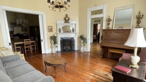 A spacious living room with hardwood flooring, a fireplace, a chandelier, and a large mirror. - Carriage Lane Inn (Murfreesboro)