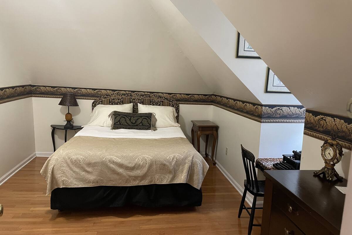 A bedroom with a large bed, a nightstand, a dresser, and a chair.