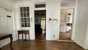 A hallway with wooden flooring, white walls, and a door leading to a kitchen area. - Carriage Lane Inn (Murfreesboro)