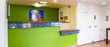 A reception desk with a green wall, a sign for extended stay, and a door labeled "Employees Only".