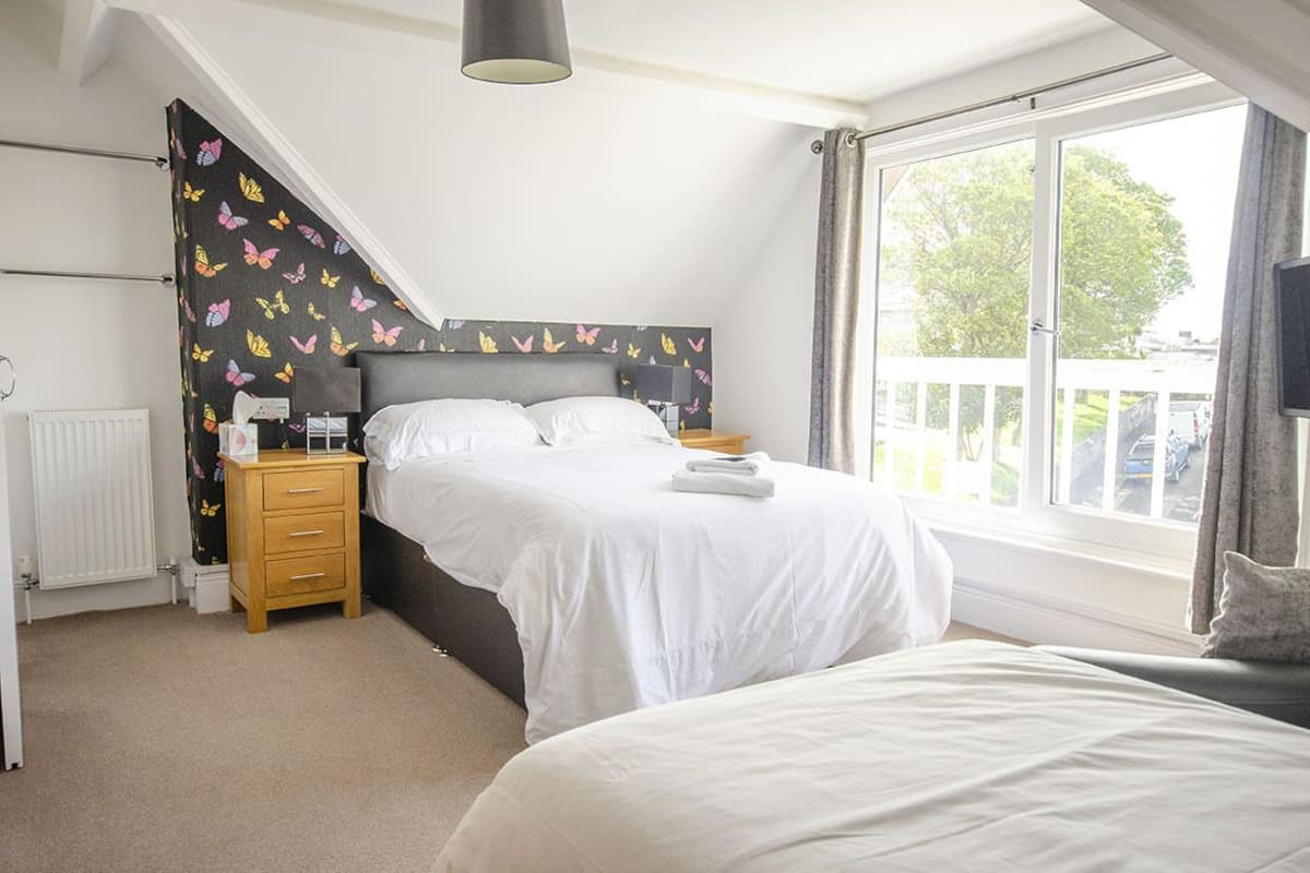 A bedroom with a bed, bedside tables, a radiator, a window with a view, and a ceiling light.