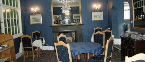 A dining room with a chandelier, a fireplace, and a large mirror.
