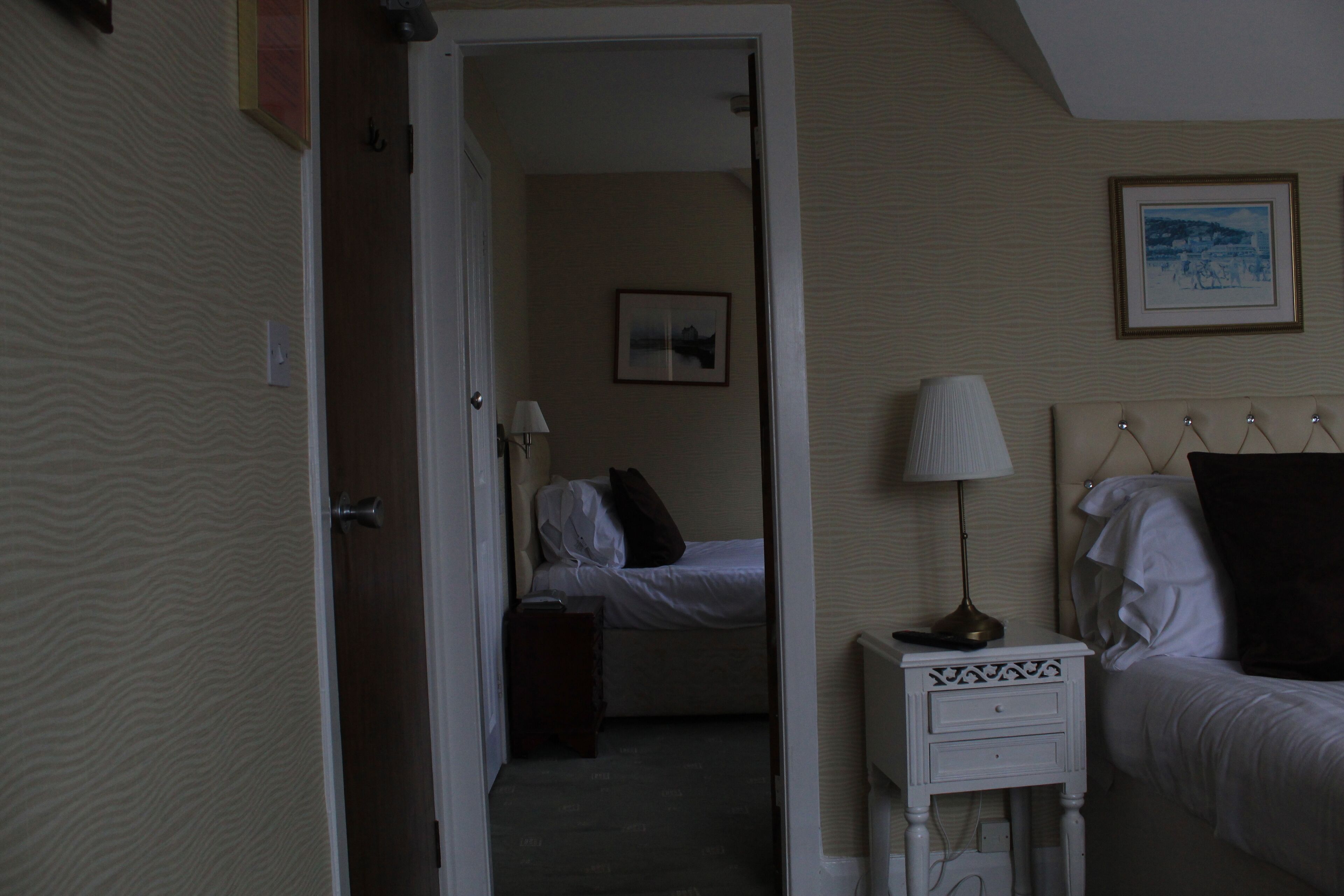 Habitación de hotel con cama, mesita de noche, lámpara y un cuadro en la pared.