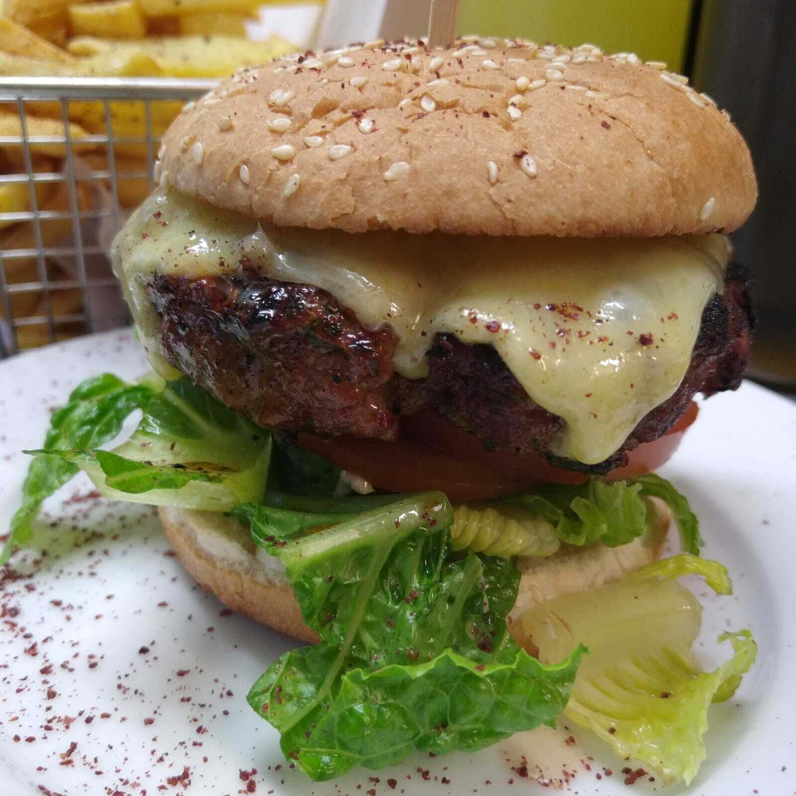 A hamburger with lettuce and cheese on a bun, served on a white plate.