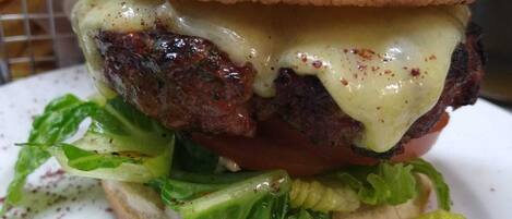 A hamburger with lettuce and cheese on a bun, served on a white plate.