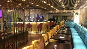 Un restaurante con zona de bar, asientos acolchados y un diseño de pared con estampado.