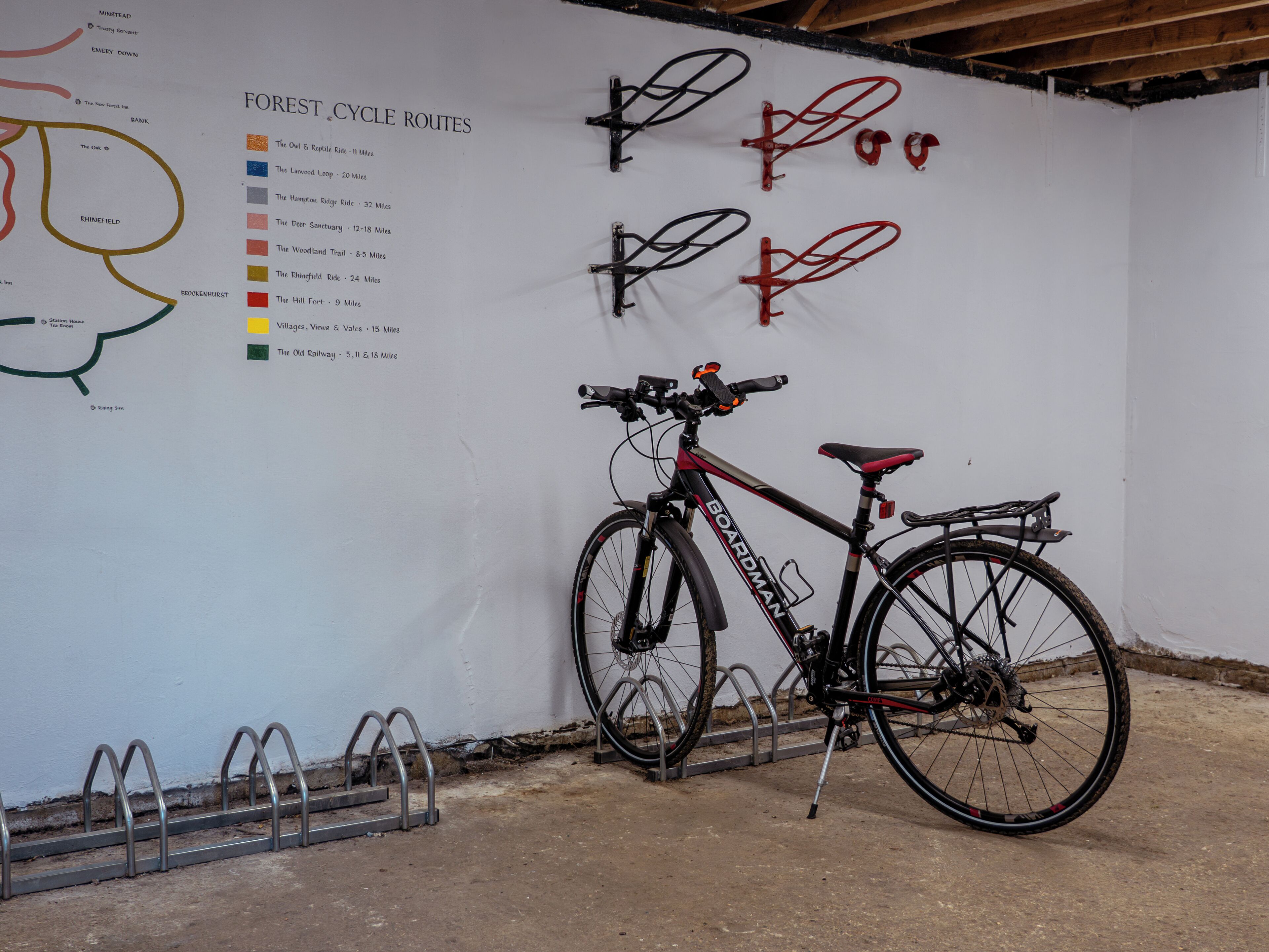 A bicycle parked next to a wall with a map of forest cycle routes.