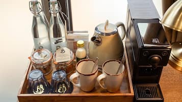 A tray with coffee-making equipment, including a coffee machine, cups, and containers of coffee and creamer.
