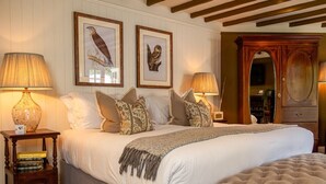 A bedroom with a large bed, two framed wall art pieces, a wooden cabinet, and two bedside lamps. - High Corner Inn (Ringwood)