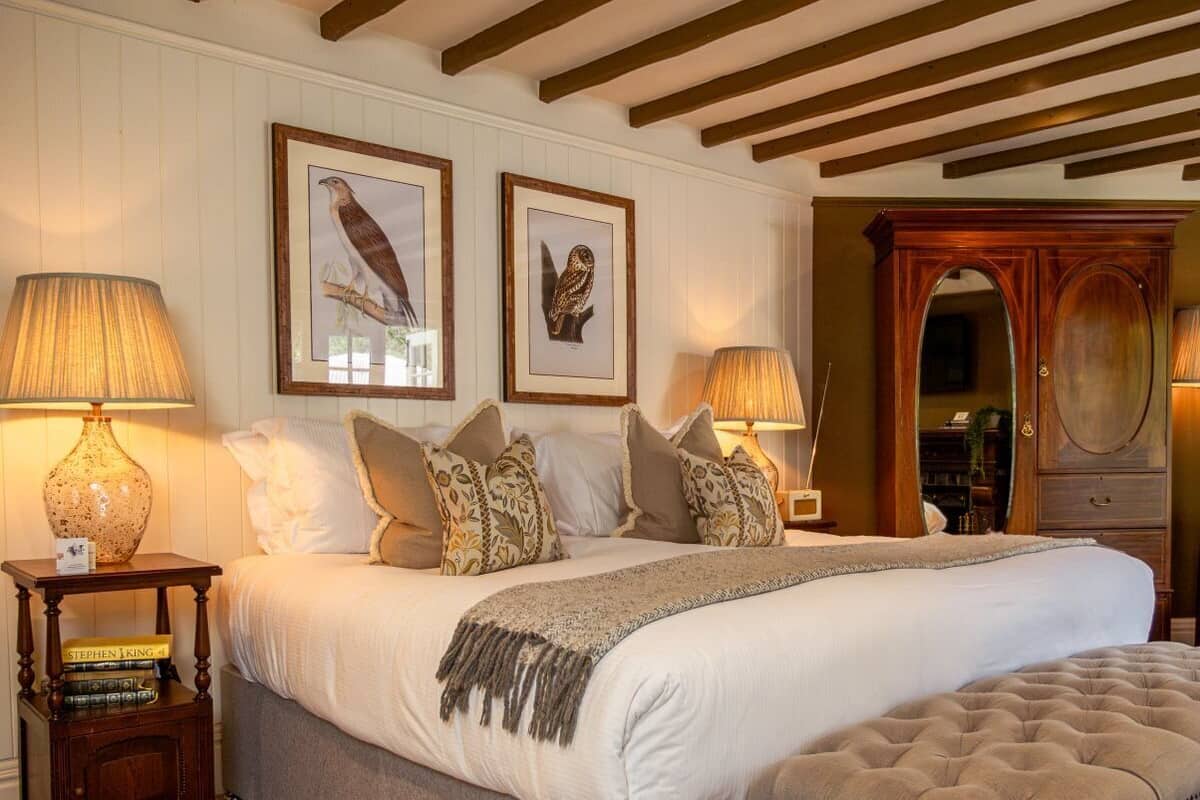 A bedroom with a large bed, two framed wall art pieces, a wooden cabinet, and two bedside lamps.