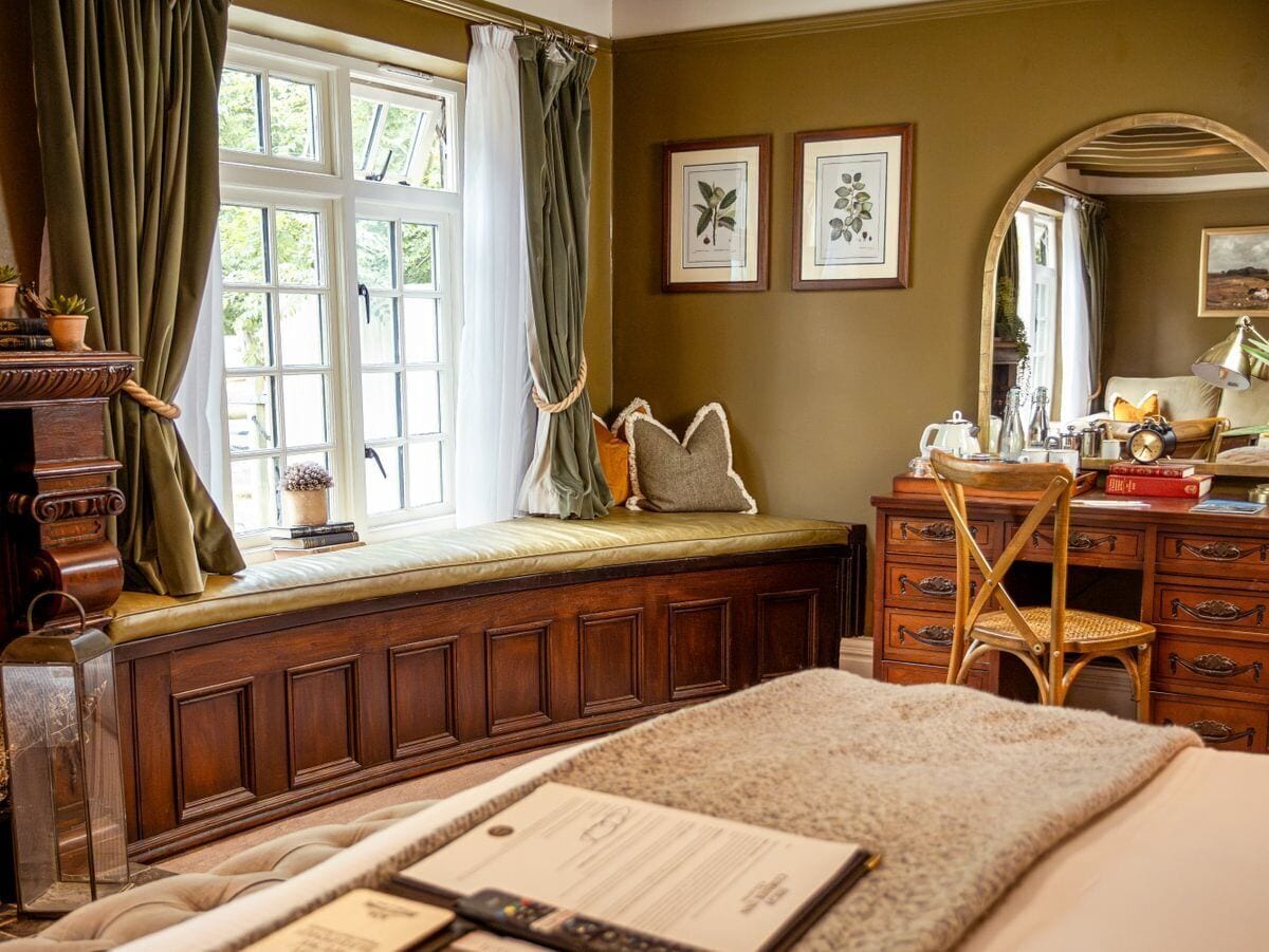 A cozy room with a built-in bench, wooden dresser, and a mirror.