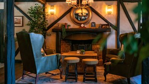 A cozy room with a fireplace, wooden beams, a chandelier, and leather seating. - High Corner Inn (Ringwood)