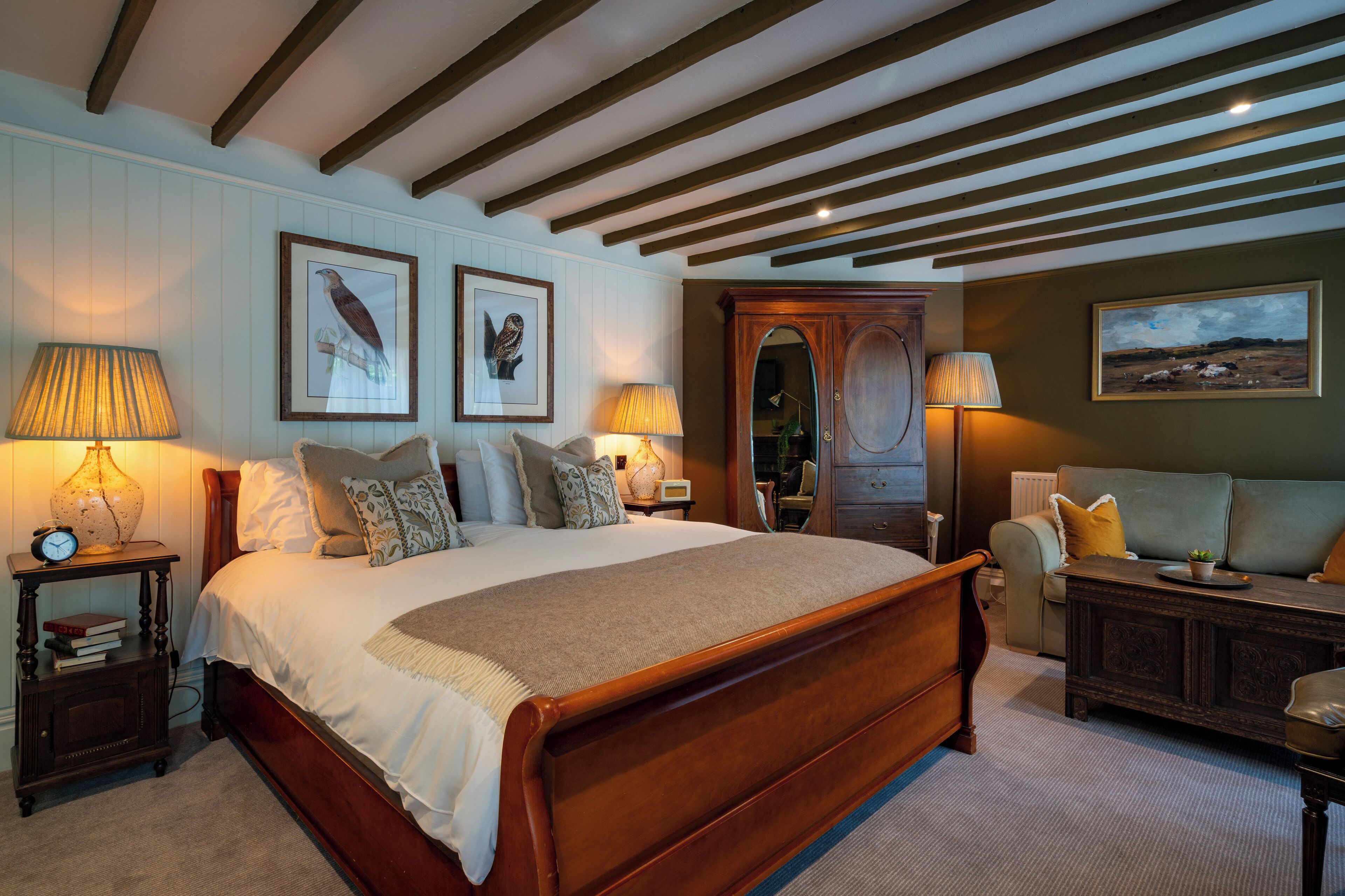 A bedroom with a large wooden bed, two bedside tables with lamps, a dresser, and a chair.