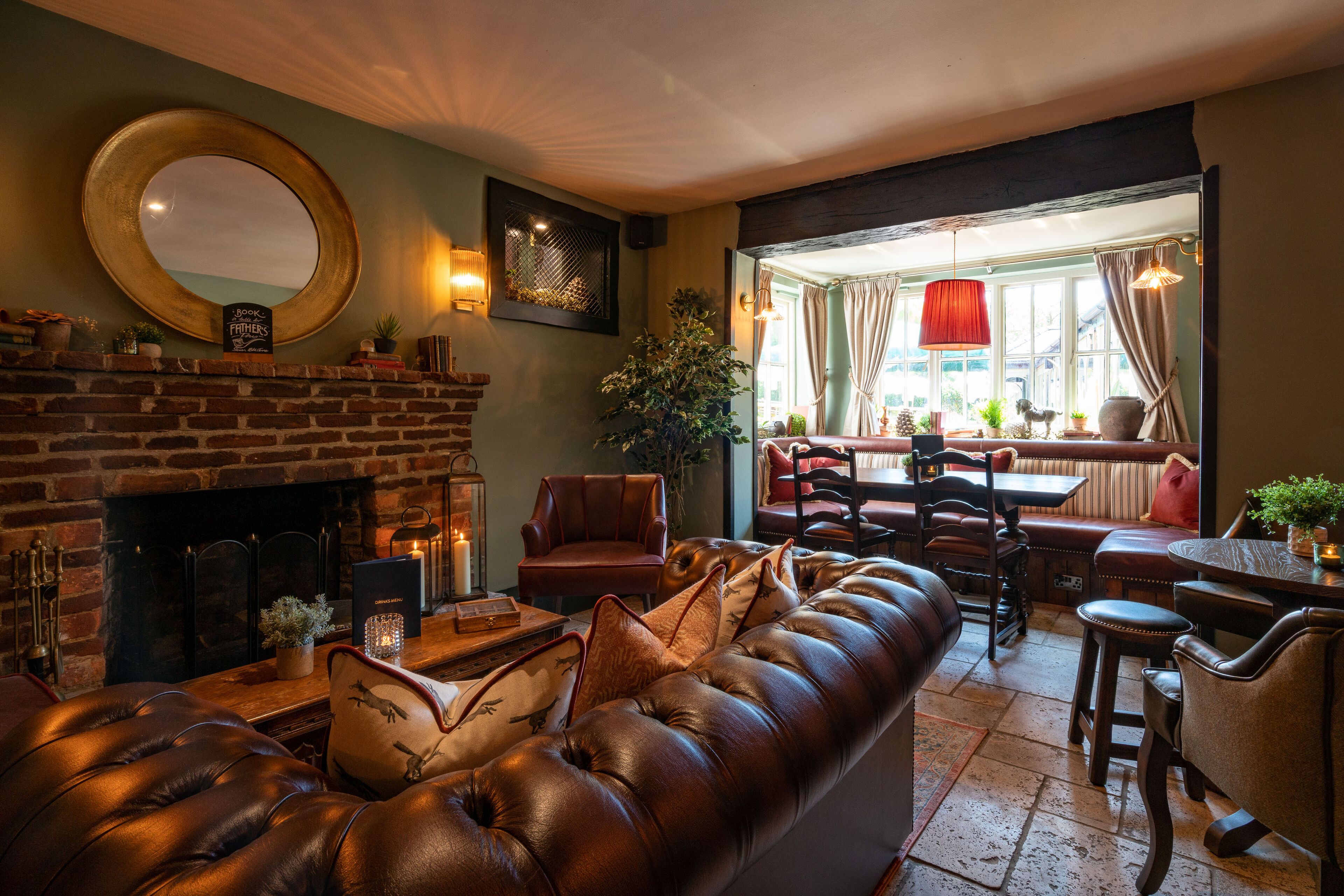 A cozy living room with a leather sofa, a fireplace, and a dining area with a table and chairs.
