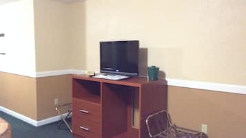 A compact room with a wooden desk, a television, a chair, and a small table.