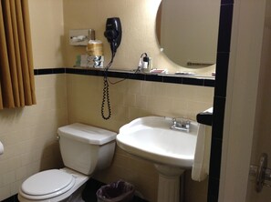 A bathroom with a toilet, sink, and hairdryer on the wall. - Briarcliff Motel (North Conway)