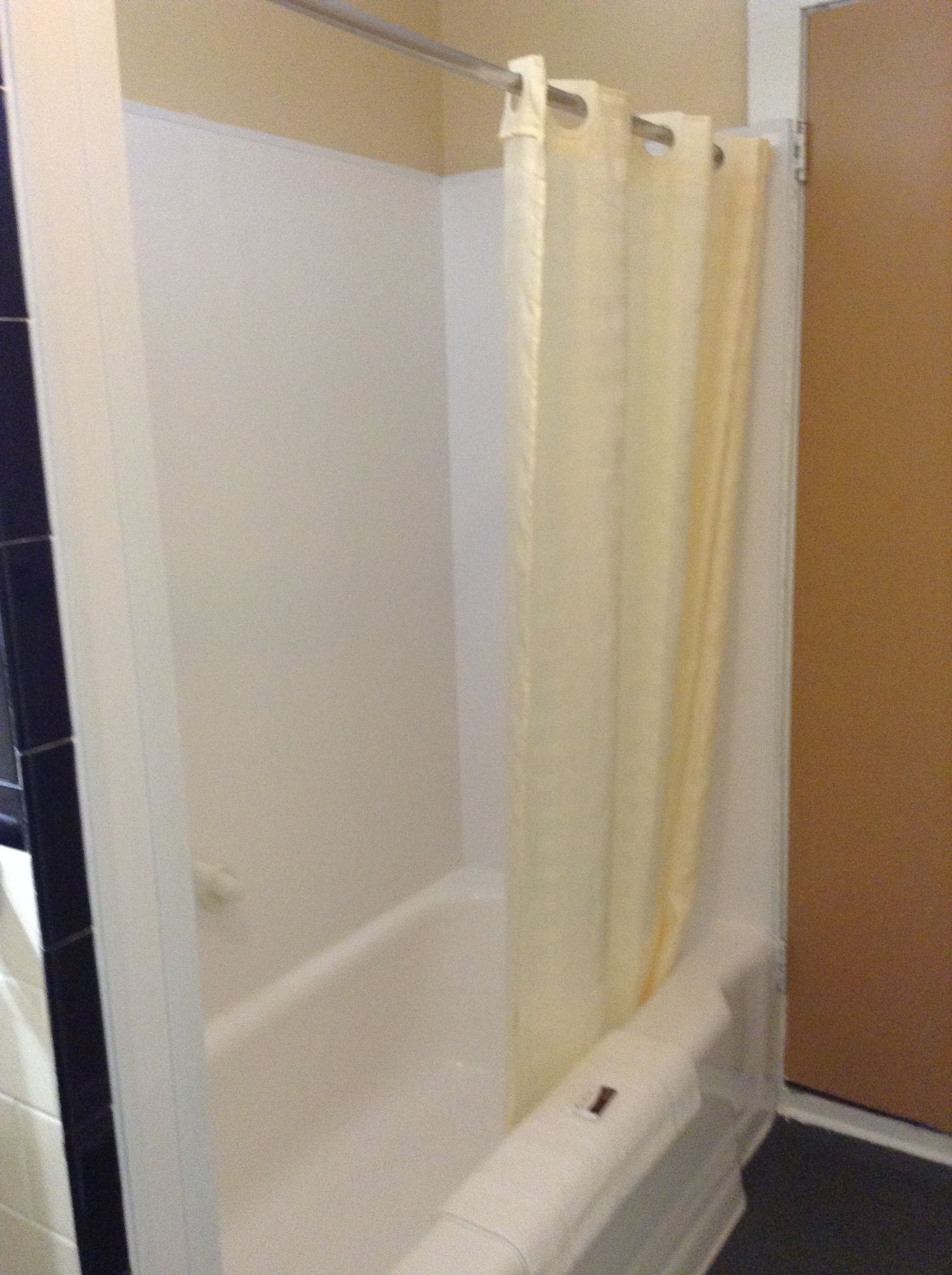Une salle de bain avec une baignoire, un rideau de douche et une porte.