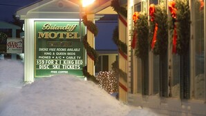Un motel avec une enseigne verte indiquant qu’il propose des chambres non-fumeurs, des lits « king size » et « queen size », et du café gratuit.
