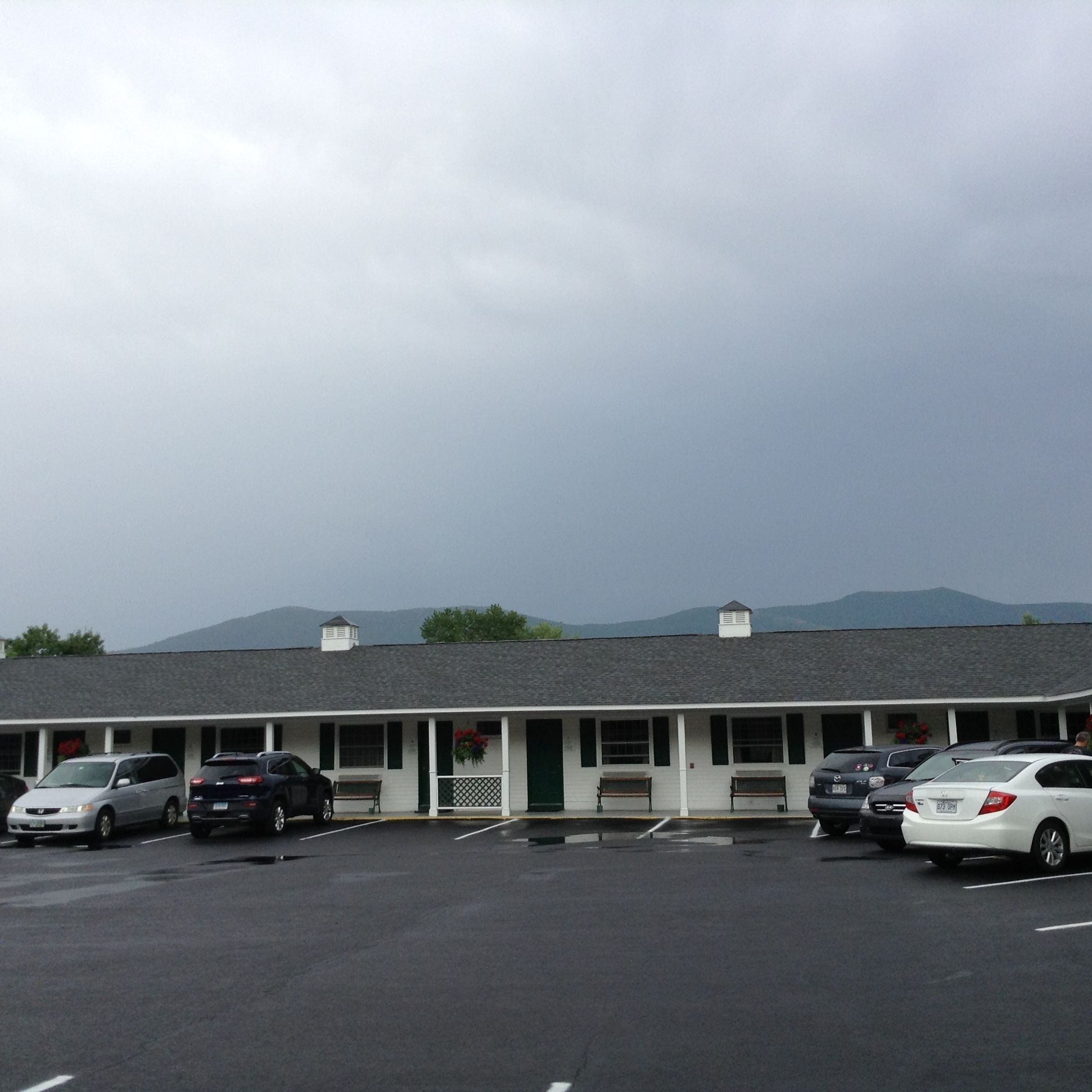A motel with a row of parking spaces and a building with a sloped roof.