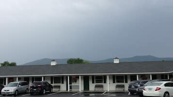 A motel with a row of parking spaces and a building with a sloped roof.