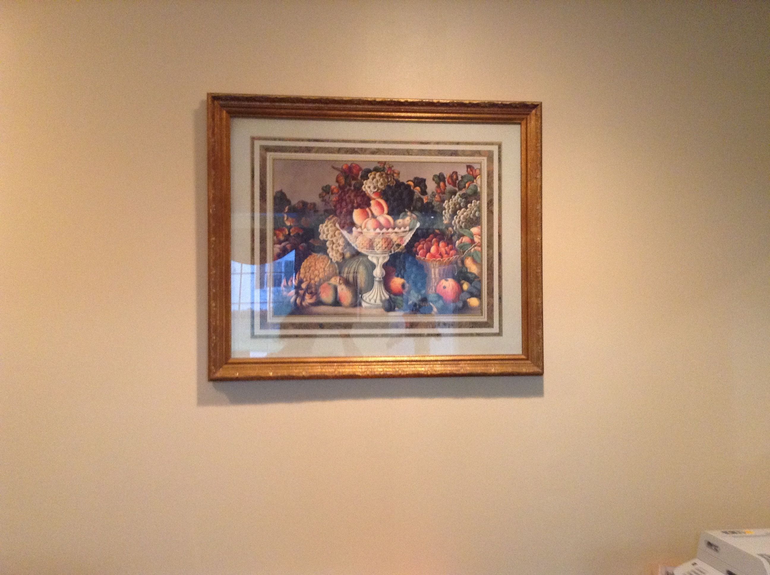 Eine gerahmte Stilllebenmalerei mit verschiedenen Früchten und Gemüsesorten an einer Wand.