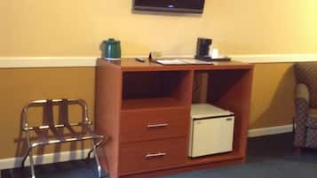 A hotel room with a bed, a desk with a computer, a chair, and a television on the wall.