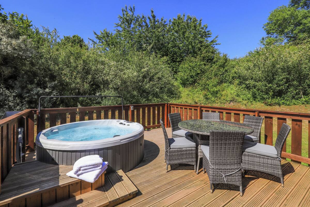 A wooden deck with a hot tub and wicker furniture.
