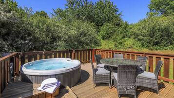 A wooden deck with a hot tub and wicker furniture.