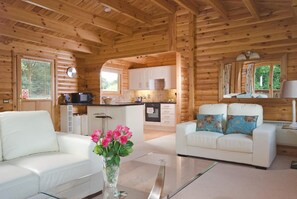 A wooden cabin interior with a living area, kitchen, and a dining table. - South Winchester Lodges (Winchester)