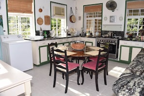 A kitchen with a dining table, chairs, and a stove. -  Barbados Chi Guest House (Bridgetown)