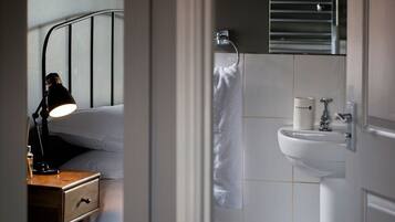 Un dormitorio con una lámpara de noche, una mesita de madera y una cama.