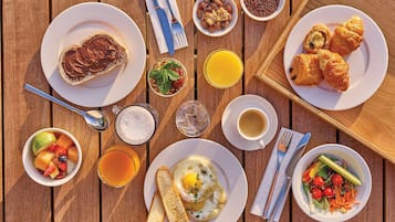 A breakfast table with various dishes including toast, eggs, fruit, and croissants.