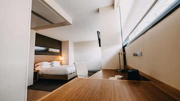 Un hotel moderno con cama, mesita de noche, lámpara y vistas de la ciudad a través de un amplio ventanal.